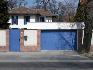 Az egyedi színű garázskapu és kertkapu jól illeszkedik a ház nyílászáróihoz